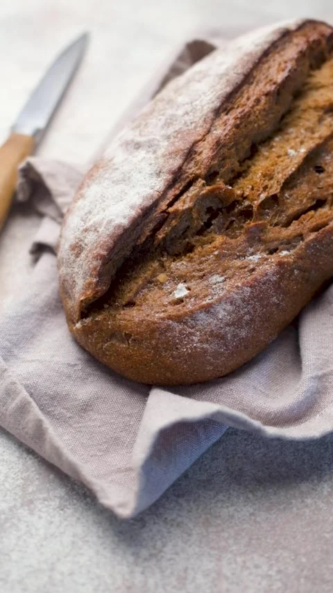 Freshly baked rye bread loaf resting on linen napkin Stock Footage 335872354