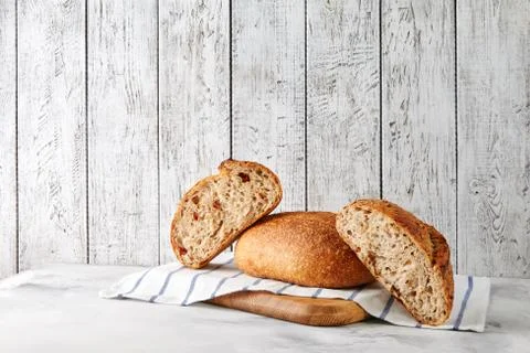 Freshly baked sliced bread lying on a towel on a wooden board on grey background Stock Photos