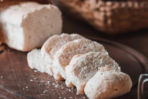 Freshly baked sliced bread on a rustic wooden board, a delicious homemade tre Stock Photos