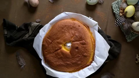 Freshly Baked Sponge Cake with Easter Eggs and Feathers in a Rustic Table Settin Stock Footage 332229192