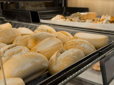 Freshly baked various bread rolls neatly displayed in a grocery store glass.. Stock Photos