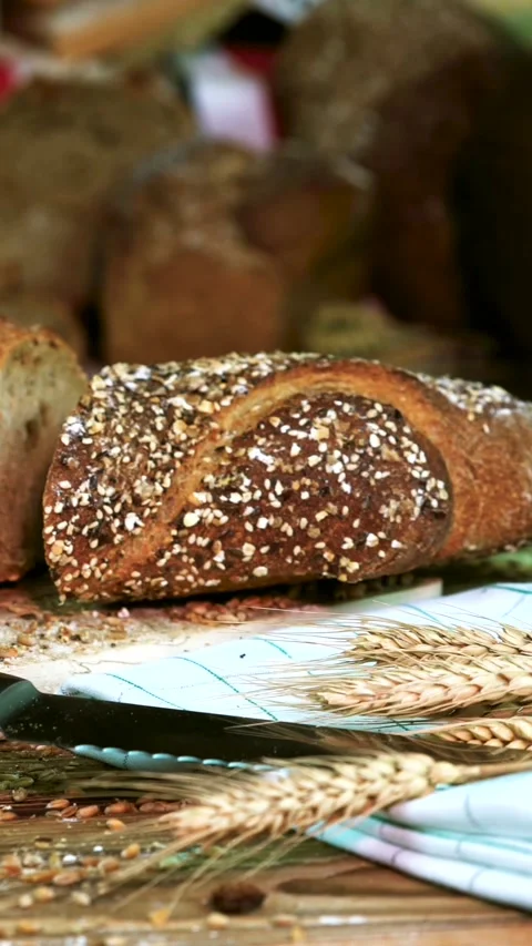 Freshly baked whole grain bread with oat topping on a rustic table with wheat Stock Footage 320752054