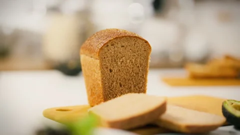 Freshly baked whole grain bread displayed on a wooden cutting board with sli Stock Footage 323805660