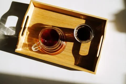 Freshly brewed black filter coffee is served on a bamboo tray on sunlit white Stock Photos