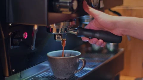 Freshly brewed coffee flows in a thin stream from the coffee machine into a 库存影片 262202995