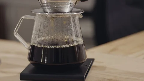 Freshly brewed coffee is poured through a filter into a glass jug, the barista Stock Footage 129638914