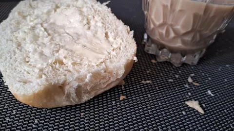 Freshly buttered bread bun served with a cold glass of milk Stock Photos