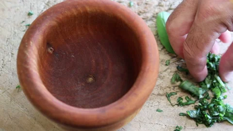 Freshly chopped basil leaves fall into a wooden mortar. Stock Footage 195949040