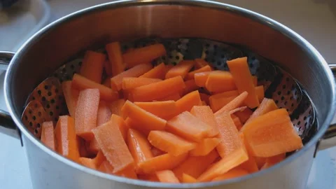 Freshly chopped carrots being added to a pot, ready to be stem cooked Stock Footage 169748243