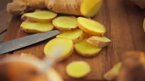 Freshly chopped ginger roots vibrant yellow flesh on a cutting board beside Stock Footage 331353604