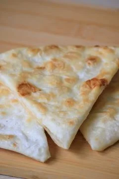 Freshly cooked crispy triangle shaped flatbread pieces served on a wooden b.. Фото
