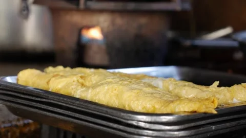A freshly cooked egg roll sits on a tray under warm light, waiting to be served Stock Footage 312110096