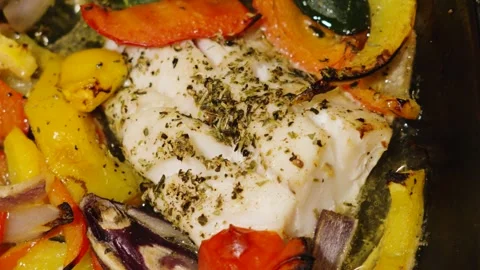 Freshly cooked traybake of wild caught atlantic Cod fillets with mediterranean Stock Footage 328680137