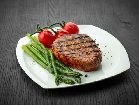 Freshly cooked veal steak with sides on white plate Stock Photos
