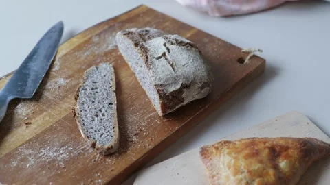 Freshly cut dark rye bread on wooden cutting board on breakfast table 動画素材 223691091