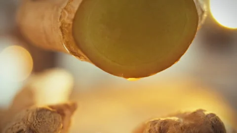Freshly cut ginger is revealed in close-up its fibrous texture evident as ju Stock Footage 331353708