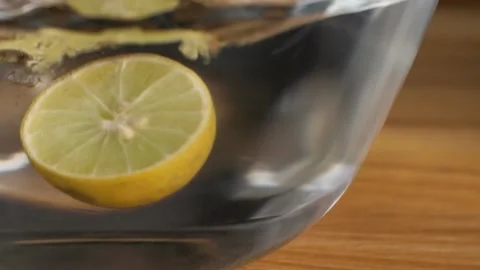 A freshly cut half lemon falling into a transparent bowl of cool pure water Video stock 151309999