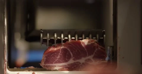 Freshly cut slice of marbled meat resting at the opening of a slicing machine 動画素材 339978793