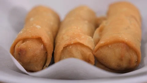 Freshly fried tasty looking spring rolls on white paper and plate close up Stock Footage 104638313
