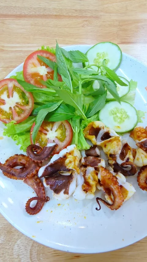 Freshly grilled octopus served on a white plate at a seaside restaurant. Seafood Stockbeeldmateriaal 336994947