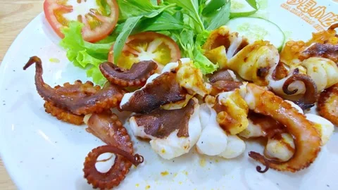 Freshly grilled octopus served on a white plate at a seaside restaurant. Seafood Stockbeeldmateriaal 337392331