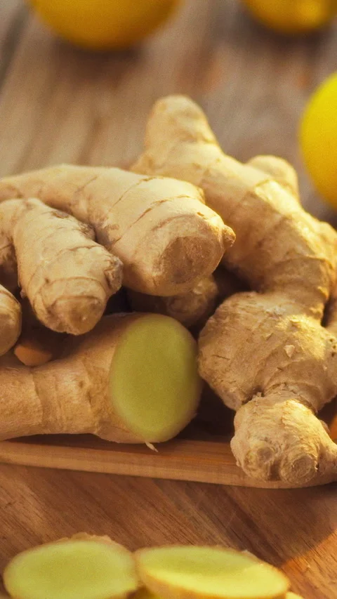 Freshly harvested ginger root and thin ginger slices lie on a wooden plate o Stock Footage 342718482