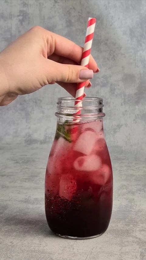 Freshly made currant lemonade in a glass with ice. A woman's hand stirs the d Stock Footage 304740958