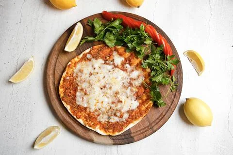 Freshly made flatbread topped with cheese and herbs on a wooden board Stock Photos