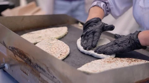 Freshly made flatbreads cooked on a grill by skilled hands. Stock Footage 310943744