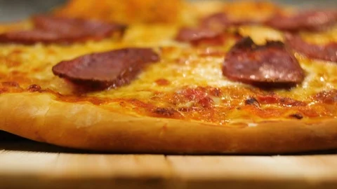 Freshly made hot appetizing peperoni pizza lays out on a wooden table by a Stock Footage 106601165