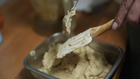Freshly made hummus paste scraped off baking spoon into metal container, Stock Footage 260299774