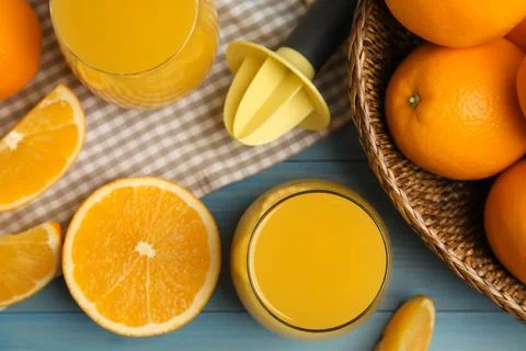 Freshly made juice, oranges and reamer on blue wooden table, flat lay Stock Photos
