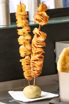 Freshly made Potato Chips on stick in outdoor food stall Stock Photos