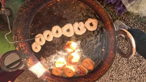 Freshly made ring-shaped doughnuts frying in a large pan of hot oil. Stockbeeldmateriaal 331146166