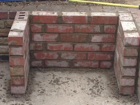 A freshly mortared brick structure rises from a concrete slab 写真素材