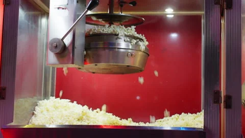 Freshly popped popcorn falling from hot kettle into display case of popcorn.. Stock Footage 338189212