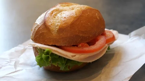 Freshly prepared crusty bread roll sandwich with ham, cheese, tomato Stock Footage 329385678