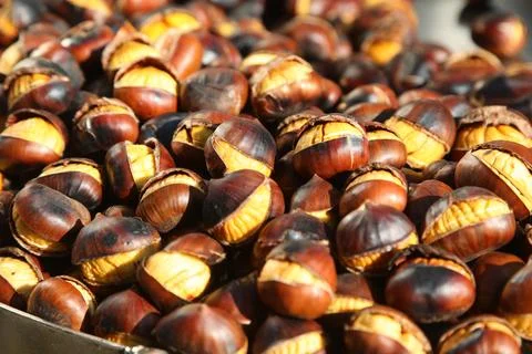 Freshly roasted chestnuts with cracked shells displayed on a street food stal Fotos Stock