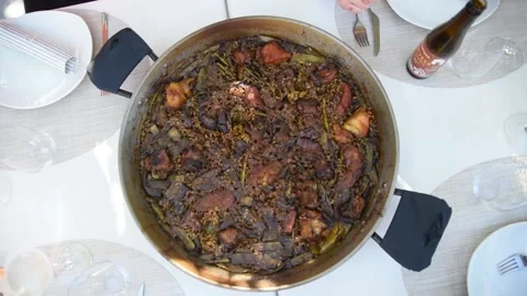 A freshly served paella on the table. Four diners are preparing to eat paella Vidéo 153273992