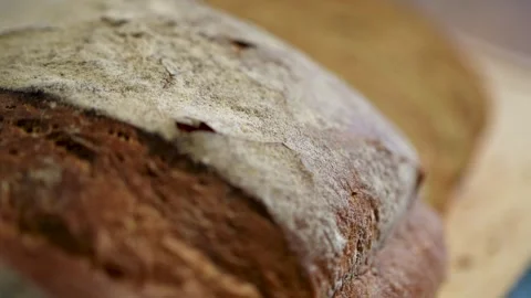 Freshly sliced, artisan bread on a rustic wooden cutting board Stock Footage 283486483