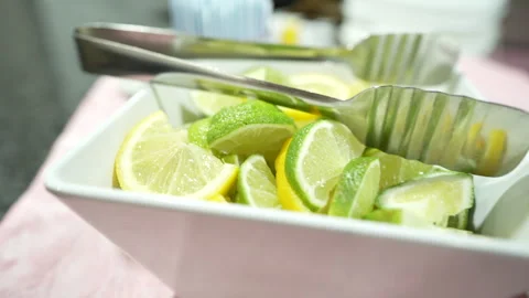 Freshly sliced lemon and lime wedges inside a white serving bowl Vídeo Stock 335270852