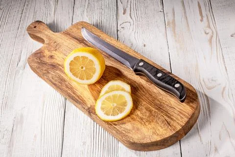 A freshly sliced lemon with a sharp kitchen knife on rustic wooden table Stock Photos