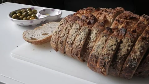 Freshly sliced olive bread served with green olives on a chopping board for a Stock Footage 312782371