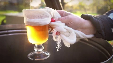 Freshly squeezed apple juice is poured into a glass which is held by a girl with Stock Footage 167608179