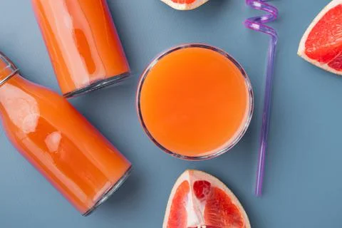Freshly squeezed grapefruit juice, on blue textured summer background, top vi Stock Photos