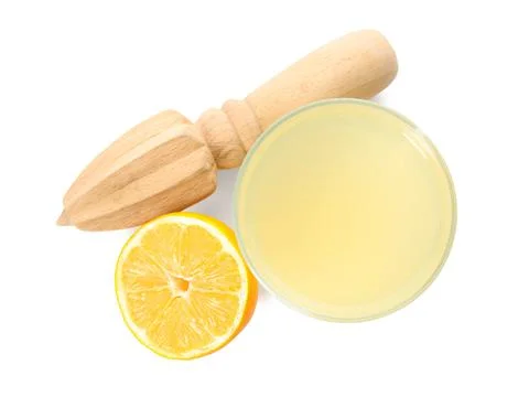 Freshly squeezed juice, half of lemon and reamer on white background, top vie Stock Photos