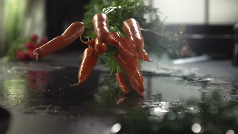 Freshly washed carrots fall in slow motion onto a shiny slate board.. Stock Footage 160895604