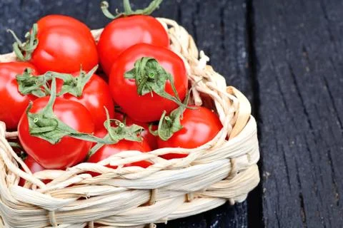 Freshness cherry tomatoes in a wicker on table Stock Photos