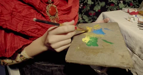 Frida painter is holding a palette while painting, famous mexican painter, 4k Stock Footage 135376392