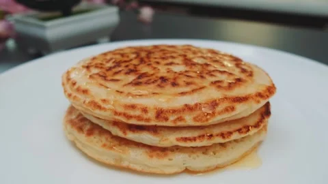 Fried appetizing pancakes with maple syrup lie on the kitchen table. Video stock 249723747